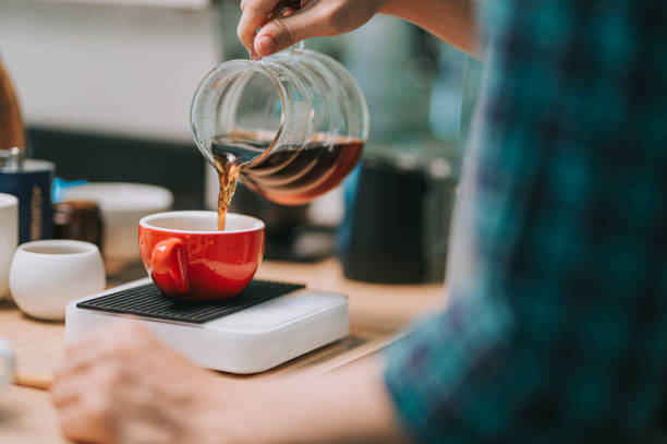 fechar a mão barista chinês asiático derramando café cervejeiro de cafeteira para xícara de café cerâmico em escala de peso - serving size weight scale scale food - fotografias e filmes do acervo