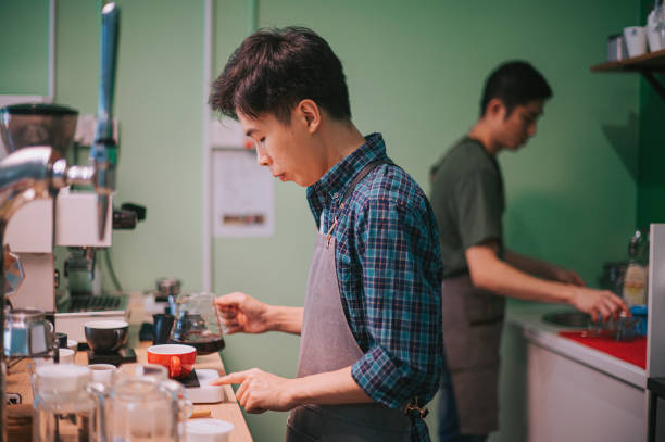 2 asiatiques chinois homme barista brassant du café travaillant dans le comptoir du bar du café - off balance photos et images de collection