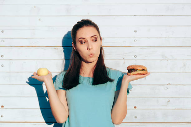 istock Woman Choosing Between a Healthy Apple and a Delicious Burger 1339751018