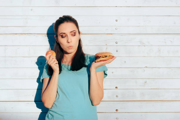 istock Woman Choosing Between a Healthy Apple and a Delicious Burger 1339751040