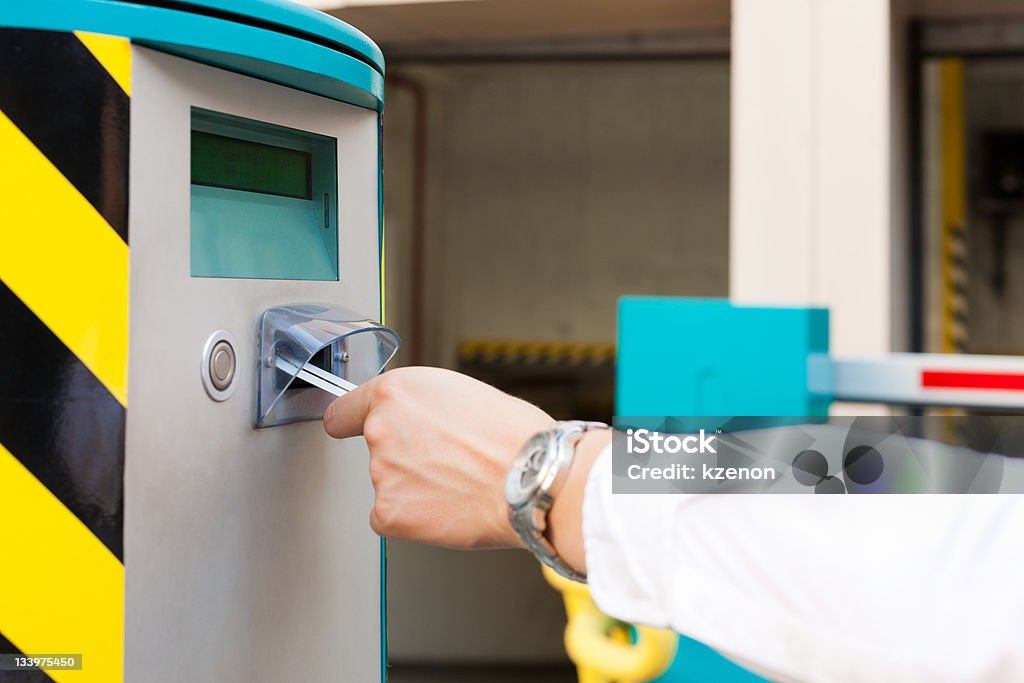 Hand is slipping parking ticket into barrier of garage A hand is slipping parking ticket into barrier of the parking garage, close-up Adult Stock Photo