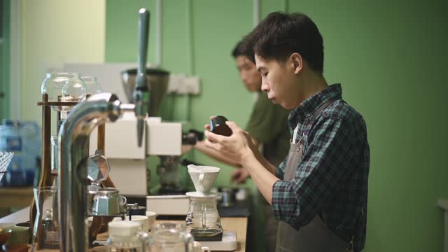 asian chinese male barista hand pouring ground coffee on coffee filter for coffee drip in cafe