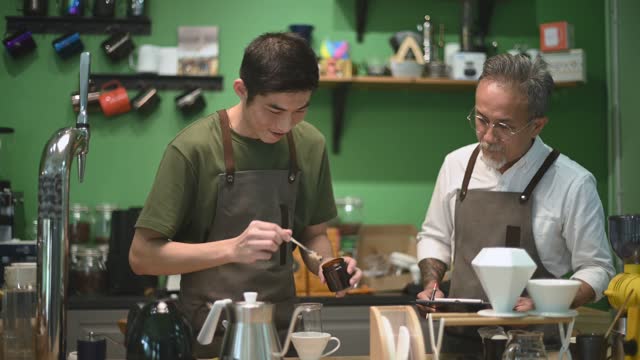 asian chines male barista cafe owner going through cold brew coffee drip training with his employee at cafe