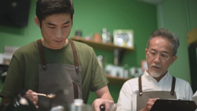 asian chines male barista cafe owner going through cold brew coffee drip training with his employee at cafe