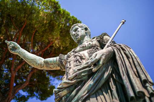 A detailed view of the bronze statue of the Emperor Gaius Iulius Caesar Augustus, also know as Octavian or Augustus, along the Fori Imperiali boulevard, in the ancient and imperial heart of Rome. This bronze statue, placed in front of the Forum of Augustus, is a copy of the marble original currently preserved in the Vatican Museums. Caesar Augustus was the first Roman emperor, revered as father of the homeland (Patri Patriae) and artecife of a long period of domination, prosperity and peace throughout the empire, known as Pax Romana or Pax Augustea. In 1980 the historic center of Rome was declared a World Heritage Site by Unesco. Image in high definition format.