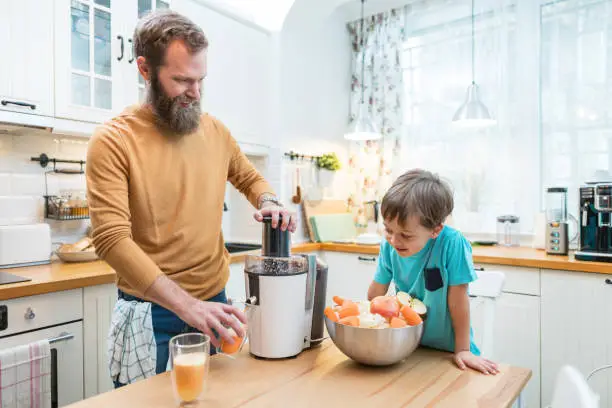 Father and son making fresh juice from fruits and vegetables