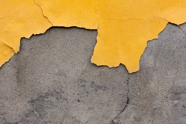 Wall with damaged peeling yellow plaster