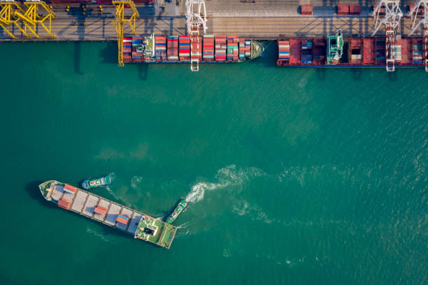 istock Aerial top view Tugboat pushing container ship to quayside for load/unload container via crane for logistics, import export, shipping or transportation 1339783875