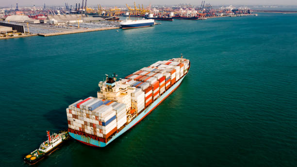 istock Container cargo ship business commercial trade import export logistic transportation container box oversea worldwide by container vessel boat freight shipping maritime with tugboat and shipping port background 1339783880