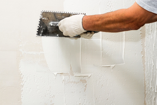 Application of plaster on the wall with a comb.