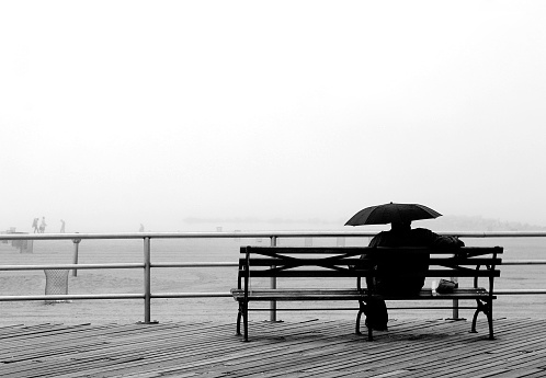 Man sitting alone with umbrella looking at the beach in the distance