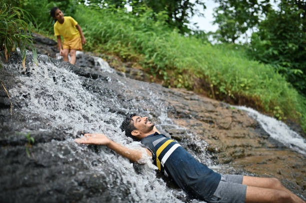 istock Young man lying and enjoying in waterfall 1339788655