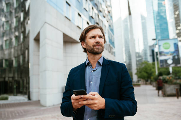 istock Mature businessman in full suit using smart phone in financial district during lockdown 1339789625