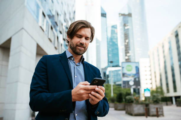 istock Mature businessman in full suit using smart phone in financial district during lockdown 1339789888
