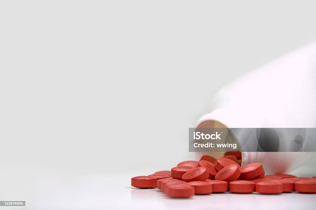 Jesus Pills ... A Way to Heaven? A factitious photo of red pills poring from a white bottle with the word "JESUS" on the pills. Copy space. Artificial Stock Photo