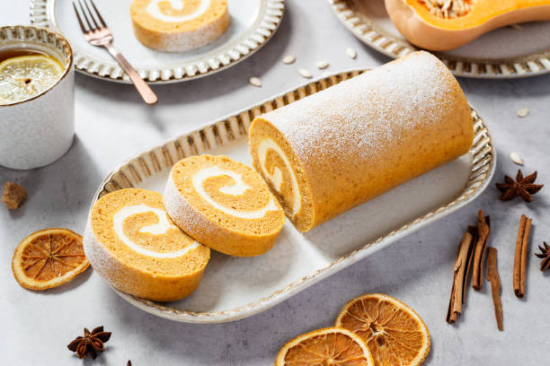 Pumpkin Cake Roll with Cream Cheese Filling. Autumn Baking. Light gray stone background.
