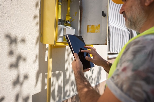 Close up technician repairing Gas Furnace using digital tablet