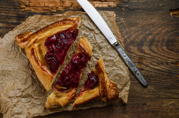 istock Homemade puff pastry with cherry on old black cooking sheet. 1339796424