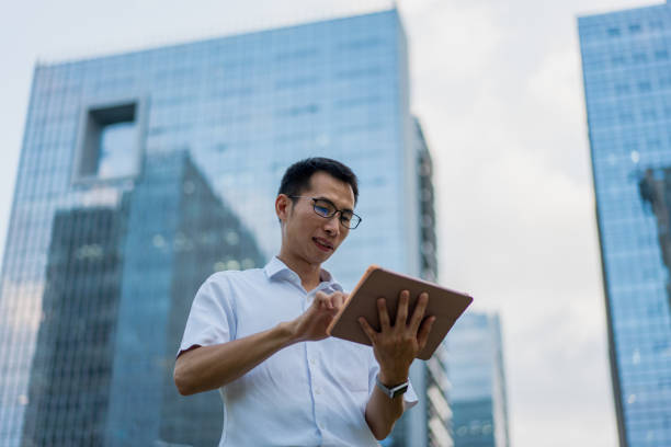 istock An Asian male white-collar worker uses a tablet outside an office building 1339799752