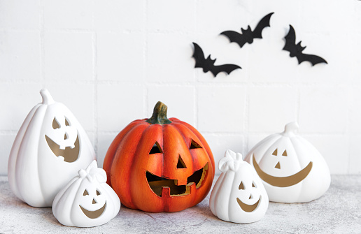 Halloween pumpkins and jack o lantern decor against a white wall with bats.