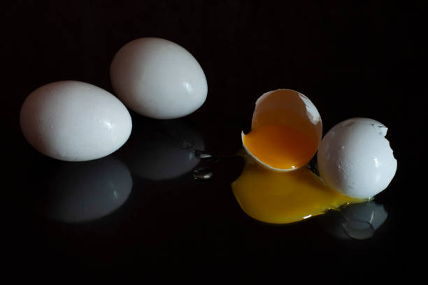 istock two whole and one broken egg with the yolk spread out on a dark background 1339805047