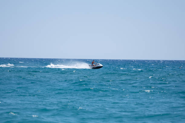 Man drives yellow jet ski on turquoise sea on a blue day stock photo