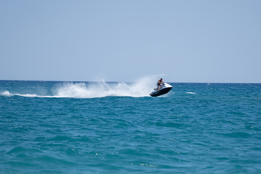 Man drives yellow jet ski on turquoise sea on a blue day