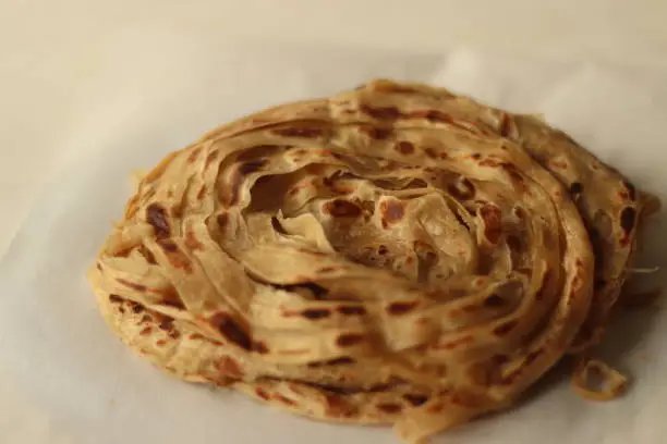 Parotta or Porotta is a layered flatbread made from Maida or Atta, alternatively known as flaky ribbon pancake. It is a favourite food item of Kerala. Shot on white background
