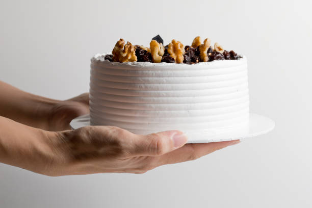 Woman holding a white cake with walnuts on top stock photo