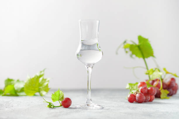 glass of grappa drink and fresh grapes on the gray background. alcohol concept - hard liqueur imagens e fotografias de stock