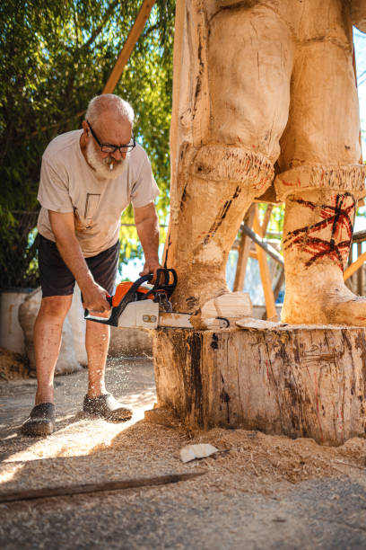Senior artist using chainsaw for making wooden statue