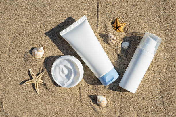 istock Unbranded cosmetic flacon with moisturizing liquid. Summer decorations, seashell and starfish, sand background. Cream or lotion. Mockup style. Beauty concept. Top view 1339819410