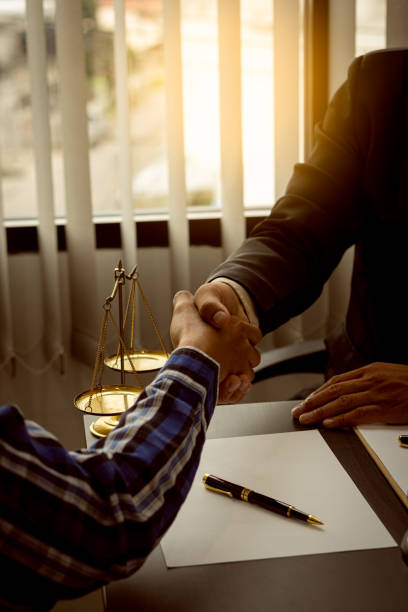 Close-up of lawyers and clients shaking hands on a table about how they successfully resolved a case with hammer and scales on paperwork. Close-up of lawyers and clients shaking hands on a table about how they successfully resolved a case with hammer and scales on paperwork. estate worker stock pictures, royalty-free photos & images