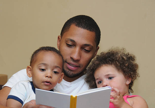 familia de dos generaciones lectura padre e hijo sobrinita - child book reading baby fotografías e imágenes de stock