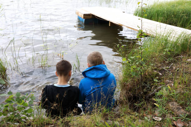 istock Two kids rest on shore of lake 1339821991