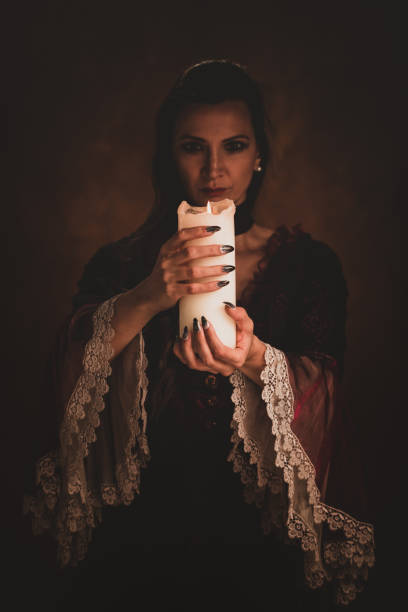 istock Witch holding white candle casting a spell in a dark room. 1339822058