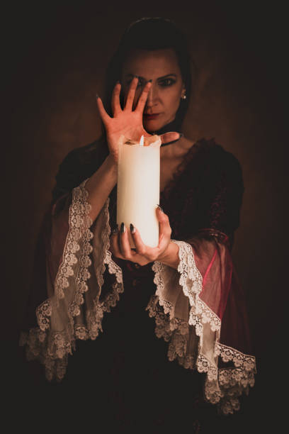istock Witch holding white candle casting a spell in a dark room. 1339822063