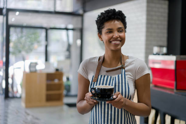 istock Happy waitress serving a cup of coffee at a cafe 1339827080