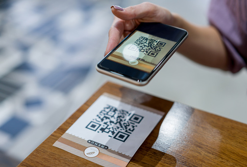 Primer plano de una mujer escaneando un código QR en un restaurante photo