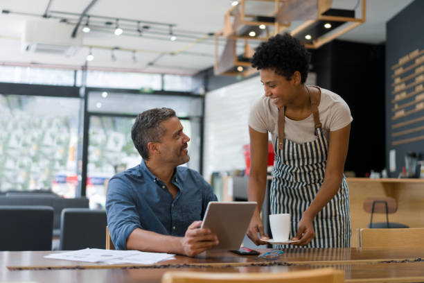 istock Happy waitress serving coffee to a man working at a cafe 1339827213