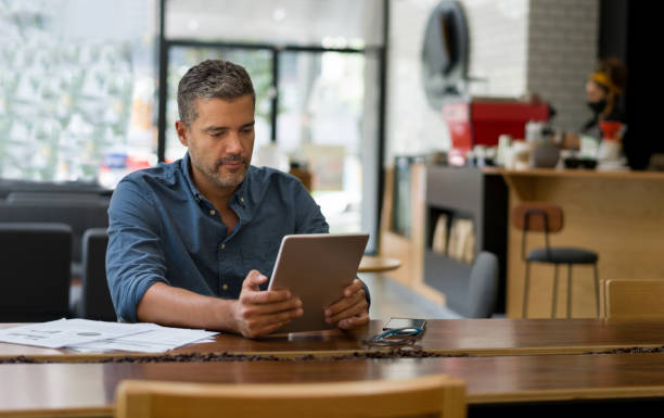 커피를 기다리는 동안 태블릿에 카페에서 일하는 사업가 - mobility working digital tablet people 뉴스 사진 이미지