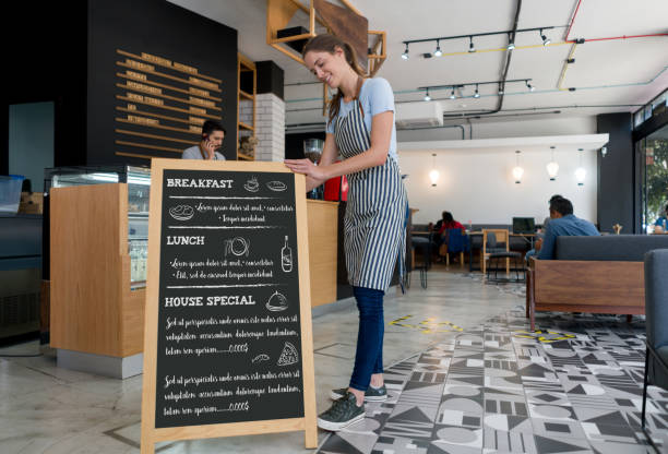 Happy waitress putting a menu board at a coffee shop
