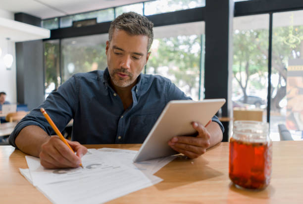 mann, der in einem café arbeitet, während er eine tasse kaffee trinkt - business plan stock-fotos und bilder