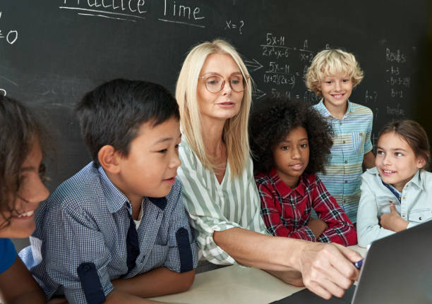 istock Happy teacher with diverse schoolkids having maths lesson sitting at desk. 1339828610