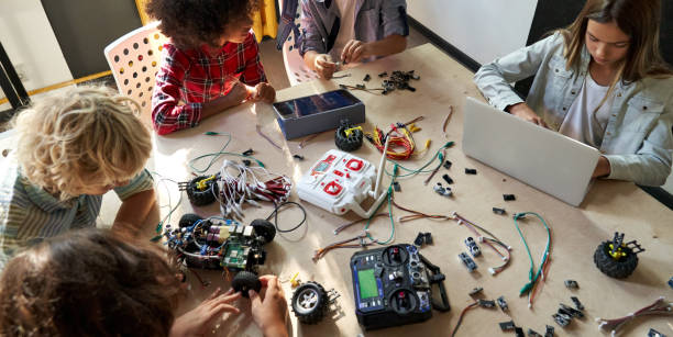 istock Group of multiracial schoolkids at stem class building robot. Table top view. 1339828618
