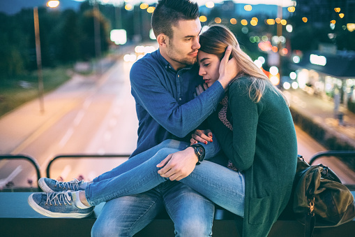 Depressed woman with her boyfriend sitting at the bridge