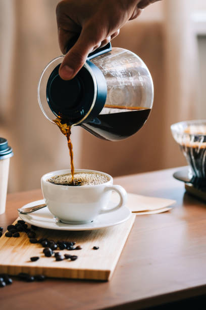 homme versant du café dans une tasse, méthode alternative de brassage du café, en utilisant verser sur le goutteur et le filtre en papier. - steep photos et images de collection