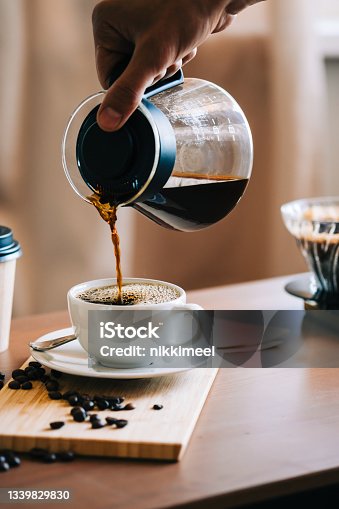 istock Man pouring coffee in a cup, alternative coffee brewing method, using pour over dripper and paper filter. 1339829830