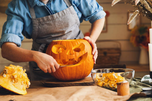 부엌에 서 서 큰 오렌지 할로윈 호박을 조각 에 앞치마에 여자 - halloween pumpkin carving jack olantern 뉴스 사진 이미지