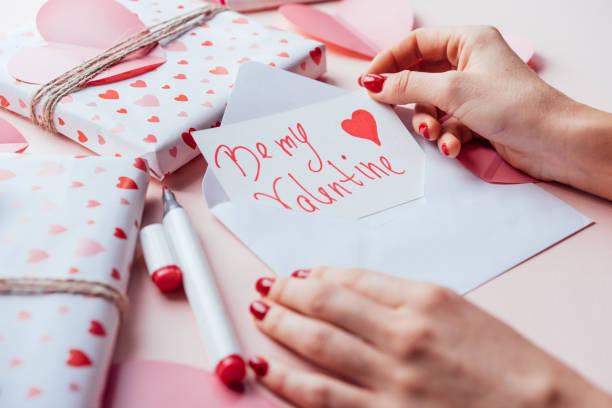 istock Close-up of hands holding a valentine card while opening an envelope. 1339838216